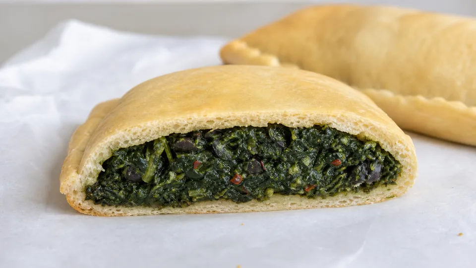 A cut Rhode Island spinach pie with dense spinach and olive filling.